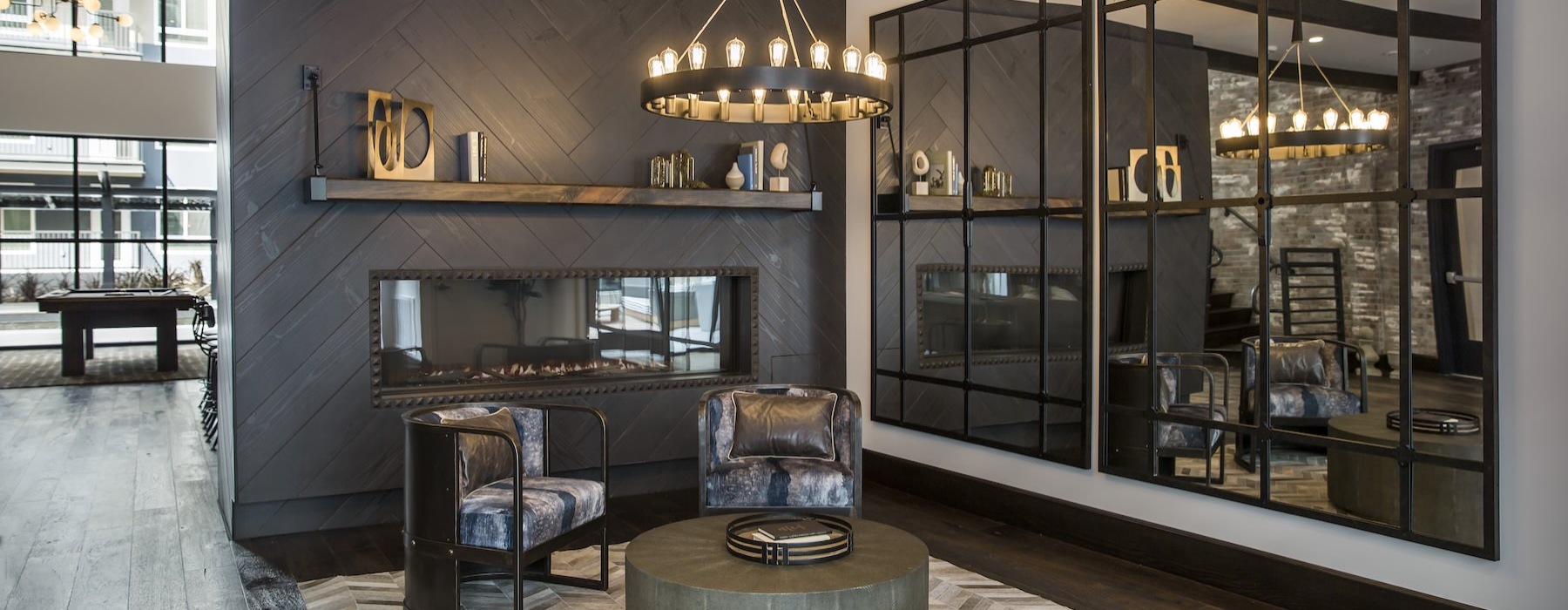 a clubroom with a fireplace, chairs and mirrors
